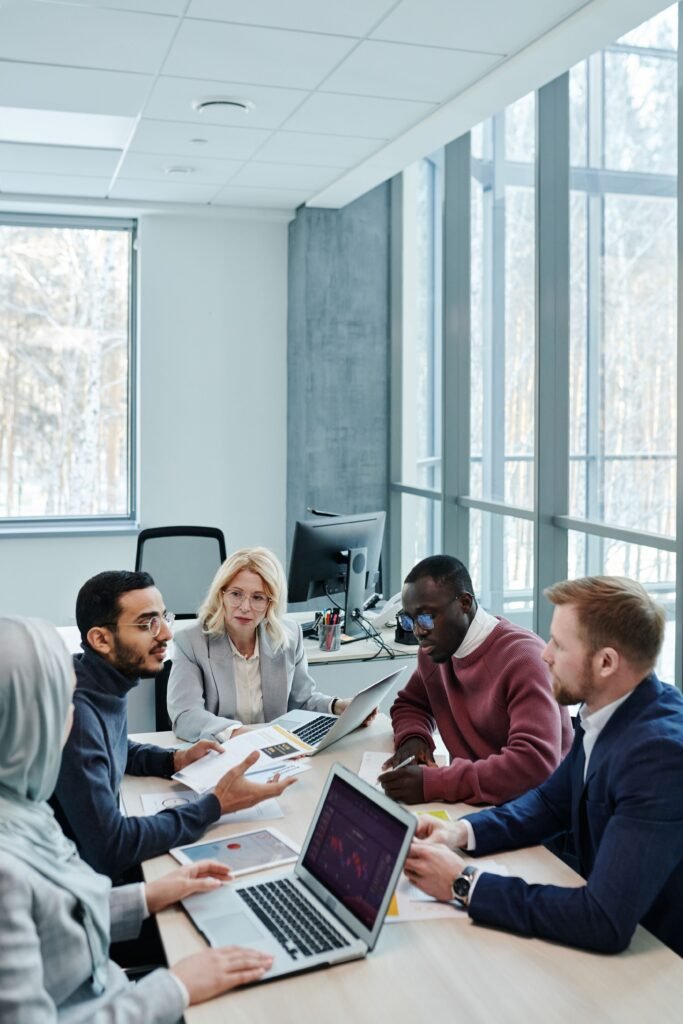 People from diverse countries sitting together in an office and having a meeting. A man is explaining something from a printout.